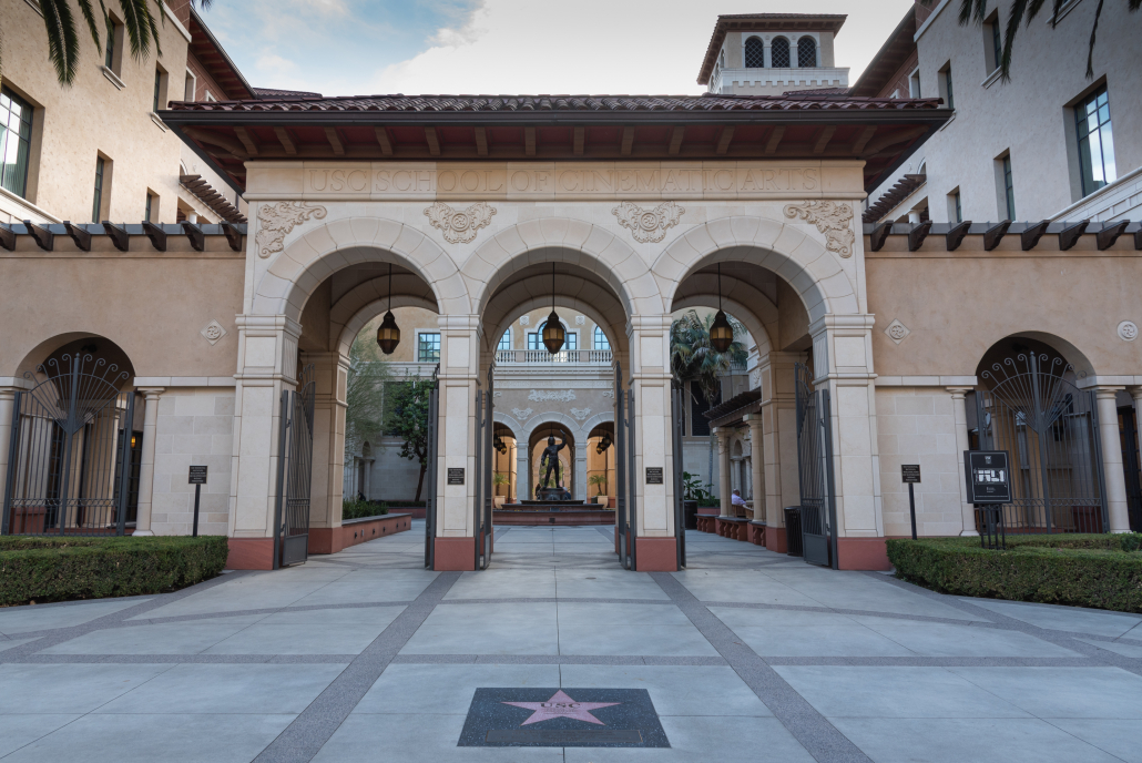 Photo of the School of Cinematic Arts, with huge arches opening into a courtyard  with a statue and fountain.