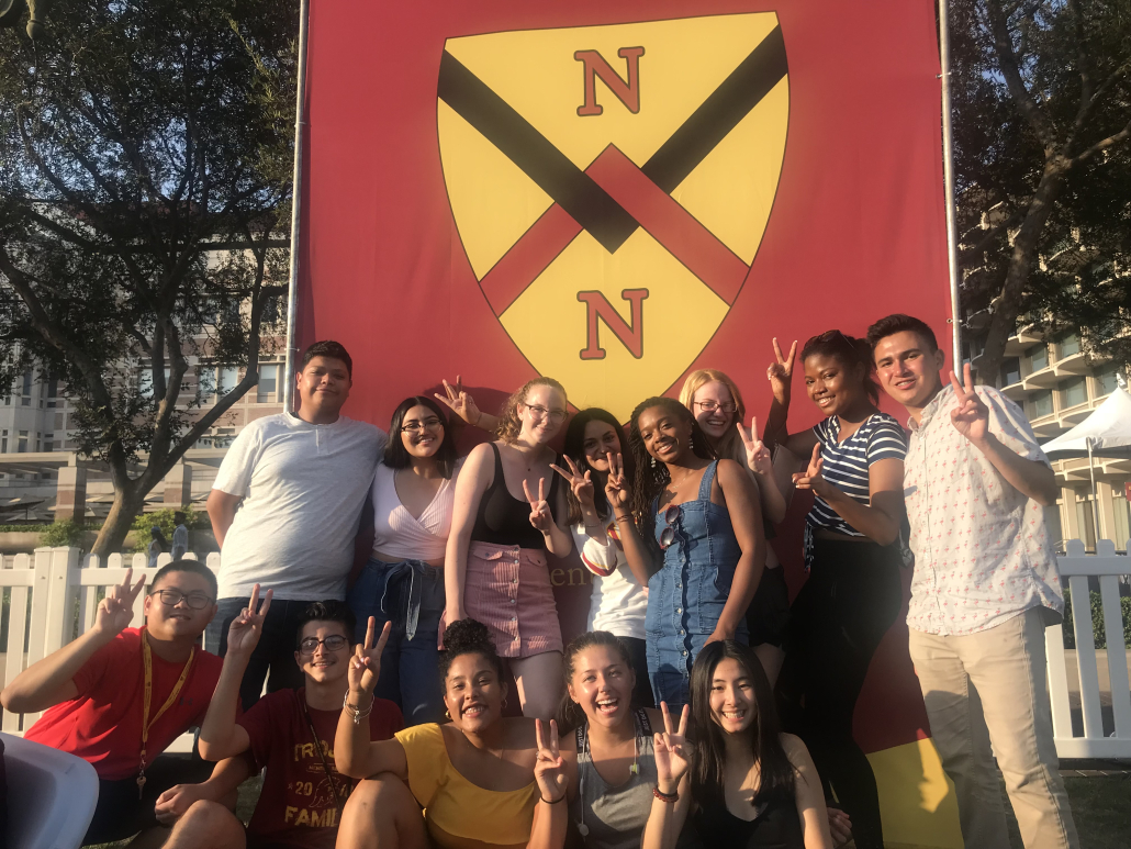 Students gathered posed outside a big banner with the New North residential hall logo.