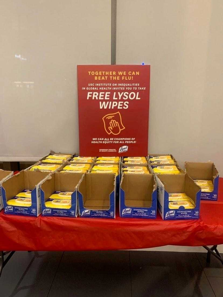 Table with stacks of Lysol Wipes. Sign that says "Together we can beat the flu! Free Lysol Wipes."