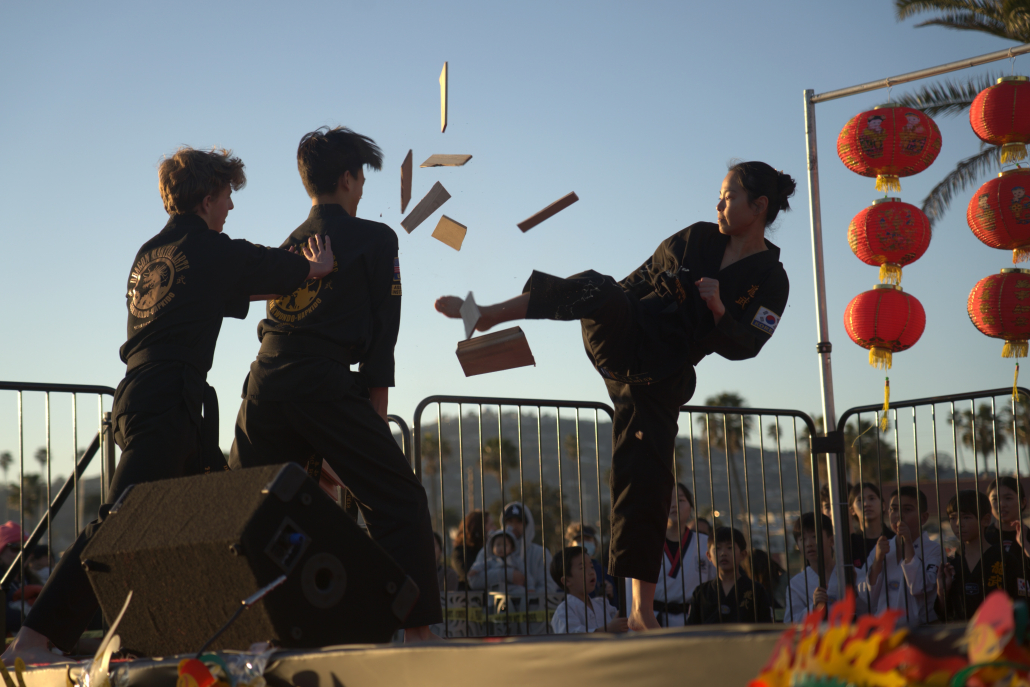 Martial Arts students break a block of wood with a kick as part of a performance.