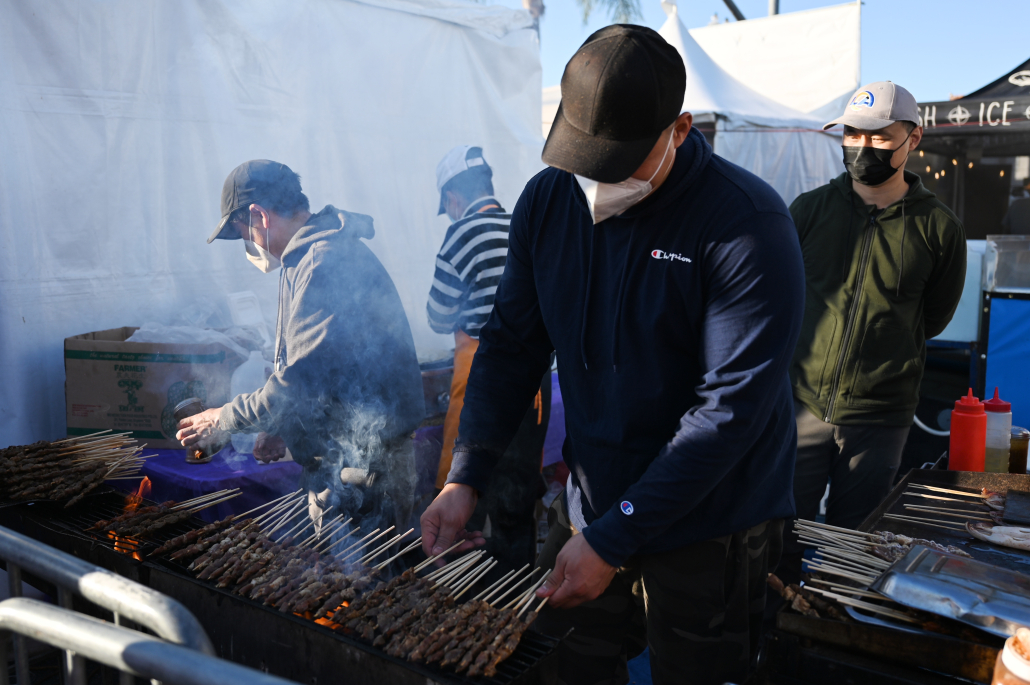 A group of men are grilling skewers of meat.