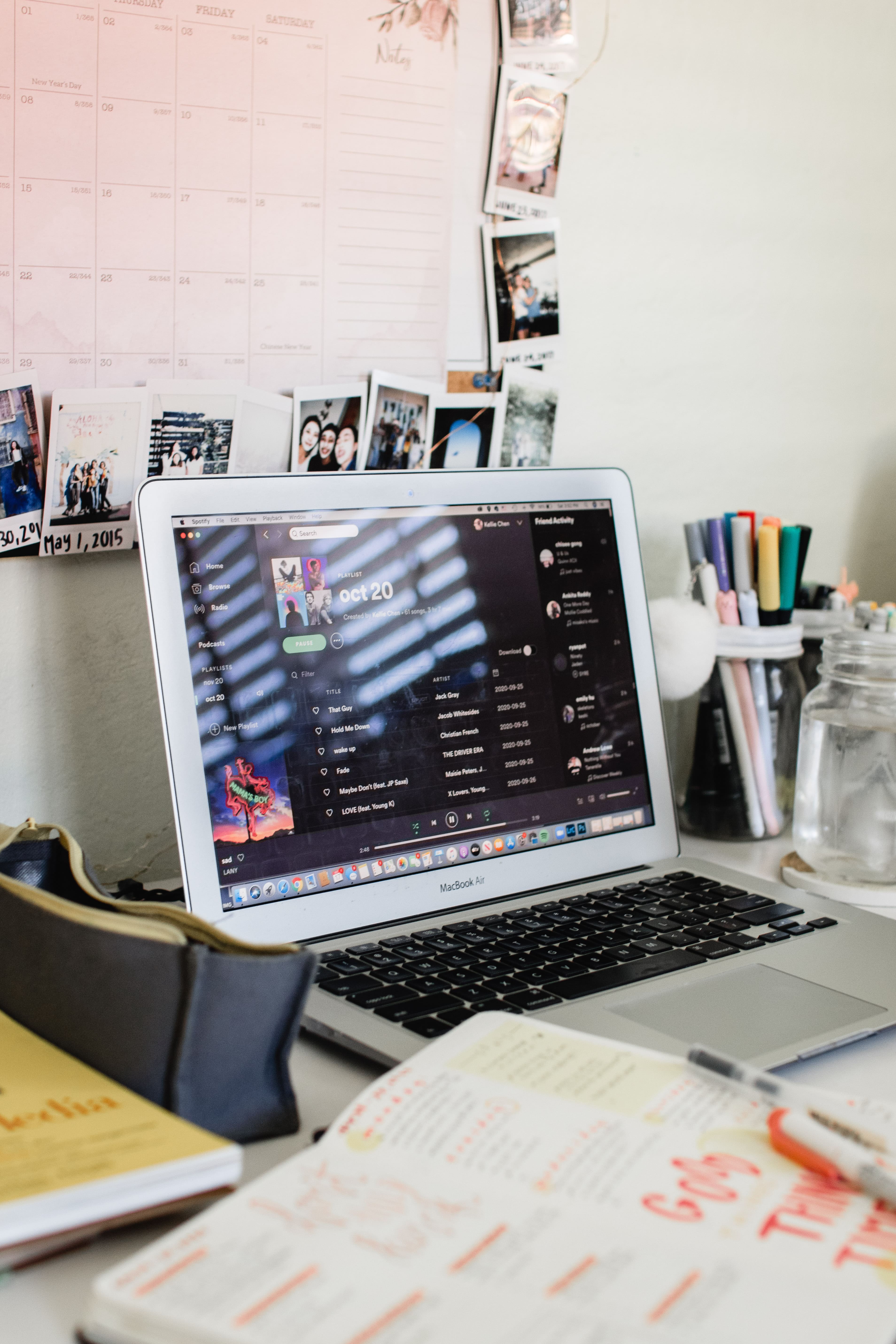 Laptop displaying Spotify and notebooks laying around