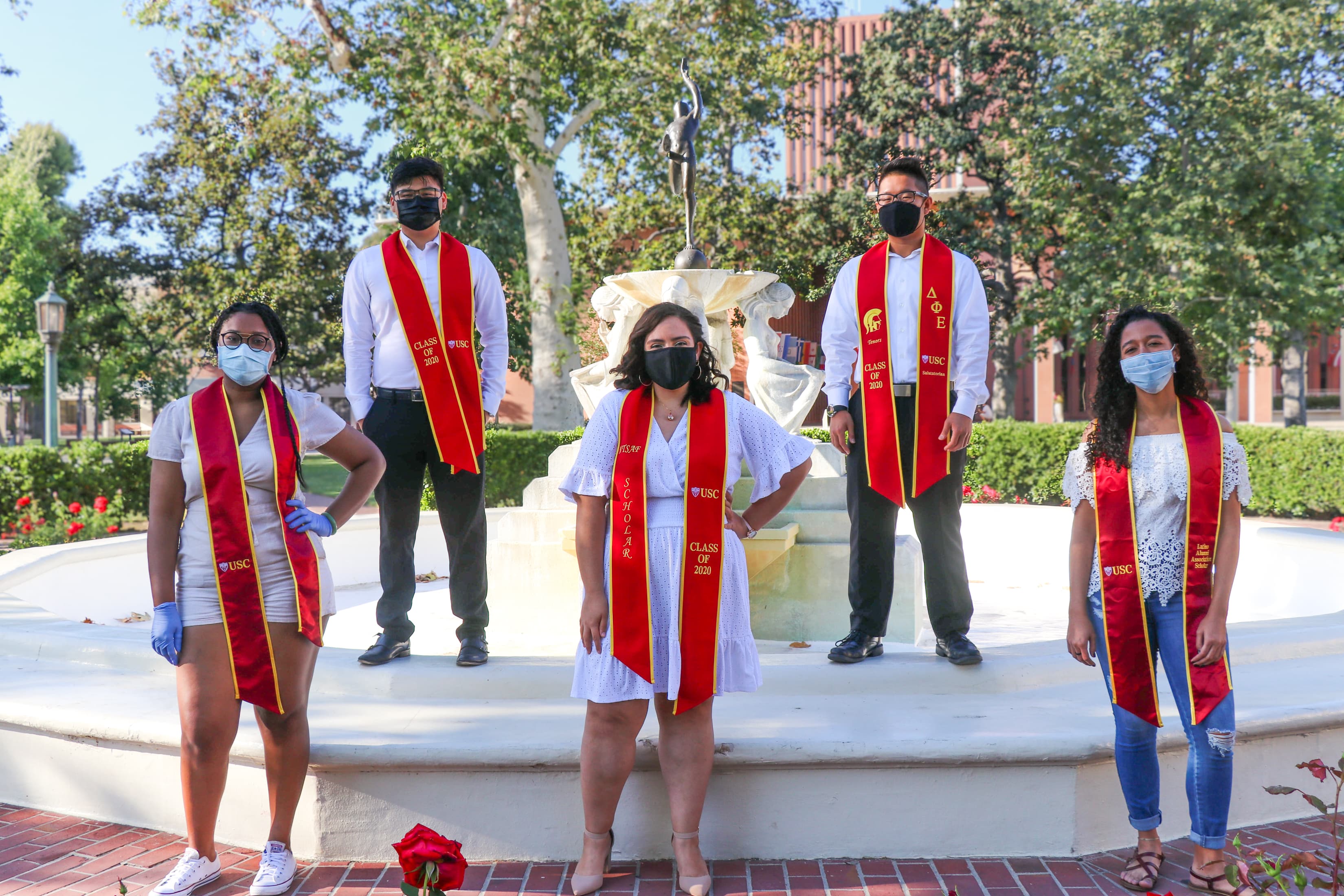 5 friends with USC grad sashes in front of water fountain