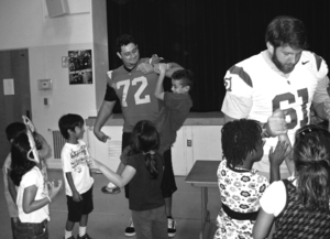 Big brother · USC football players Kristofer O’Dowd and Martin Coleman teach local school children about unconventional learning. - Photo courtesy of SOS Classroom