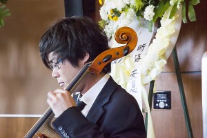 安息. 昕海 · Yoshika Masuda plays the cello with the message “Rest in Peace, Xinhai” hanging behind him at the memorial on Tuesday night. — Ralf Cheung | Daily Trojan