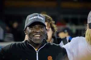 Head coach Keidane McAlpine grins from atop the podium during the trophy presentation. McAlpine is only the second African-American coach to lead his team to an NCAA championship. - Photo courtesy Madeleine Roche