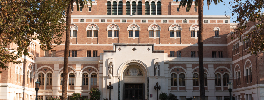 This is a front view of the entrance to Doheny Memorial Library. It is a sunny afternoon and the half of the building is in the shade.