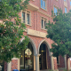 The image displays the Cale Residential College building from the front. The college is framed by two trees. Visible in the photo are a fire hydrant, a trash can and recycling bin.