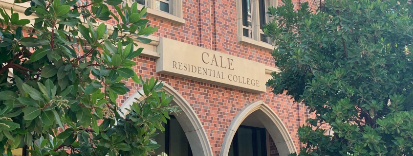 The image displays the Cale Residential College building from the front. The college is framed by two trees. Visible in the photo are a fire hydrant, a trash can and recycling bin.