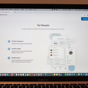 An image of a Macbook Air laptop screen that displays the “For Parents” page of the website www.getcarline.com. On the left of the screen, there are three points that list the application’s features, reading “Guardian management,” “Schedule changes” and “Playdate support.” To the right, there is a graphic of a smartphone where the application where some features of the application are artistically displayed. On the top right there is a blue button that reads “Request demo” in white letters.