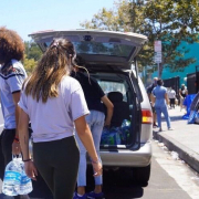 Volunteers take gallons of water out of a van parked by Skid Row.