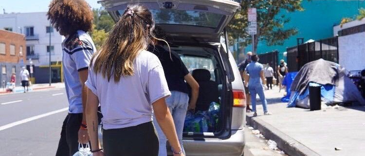 Volunteers take gallons of water out of a van parked by Skid Row.