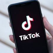 The image shows an iPhone with a blank screen displaying the Tik Tok symbol, a musical note, with the words "Tik Tok" written below it. A hand is holding the phone.