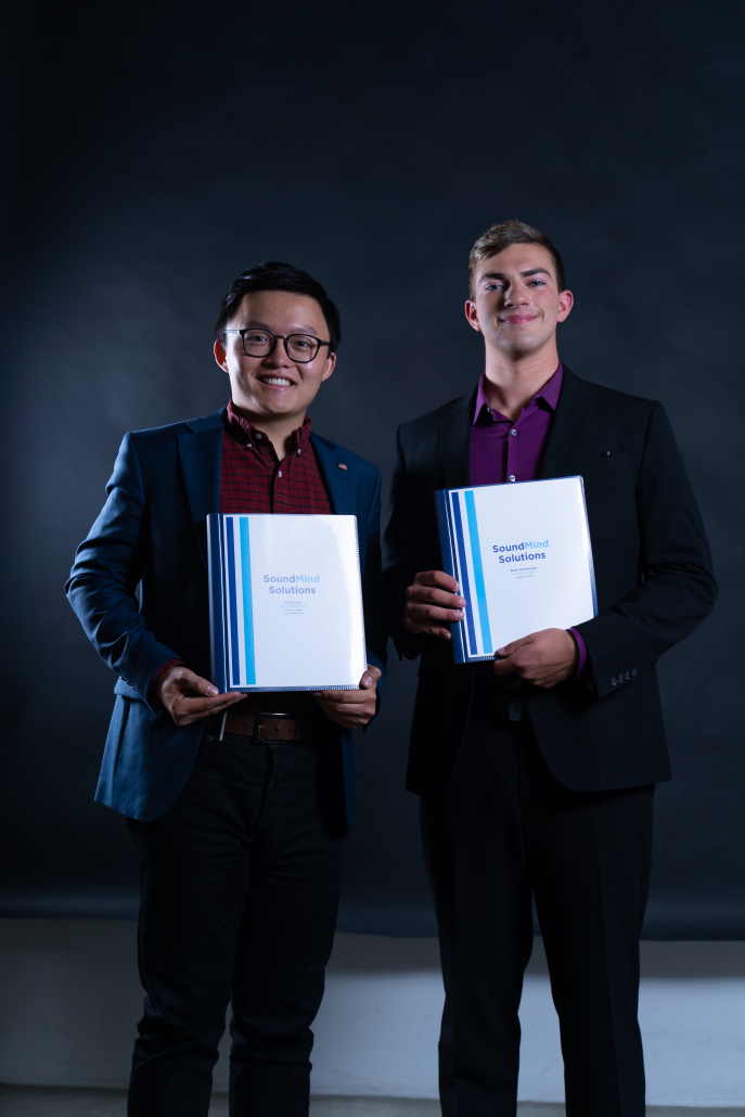 Photo of Brian Femminella and Travis Chen holding binders that read “SoundMind Solutions.”