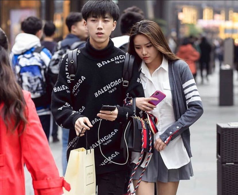 Two people in streetwear walking down a busy street. 