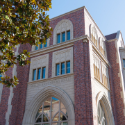 A photo of the red-brick building of the new Annenberg with tree branches