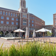 Photo of the red brick buildings of the USC village with green grass at the bottom of the image