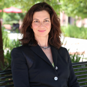 A medium shot of Sarah Gualtieri sitting on a green branch in a blazer