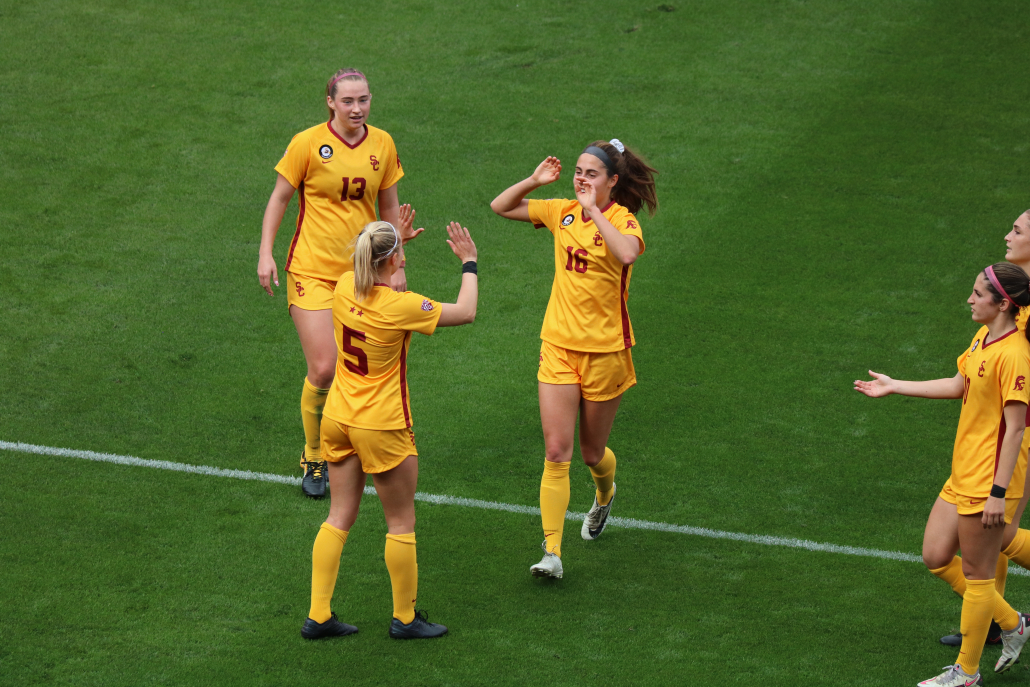 Members of the women's soccer team high-five on the field. 