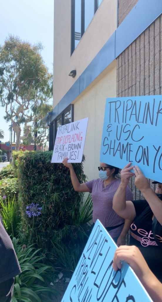 Protestors hold signs that read "Tripalink stop displacing Black + brown families!" and "Tripalink & USC shame on you" 