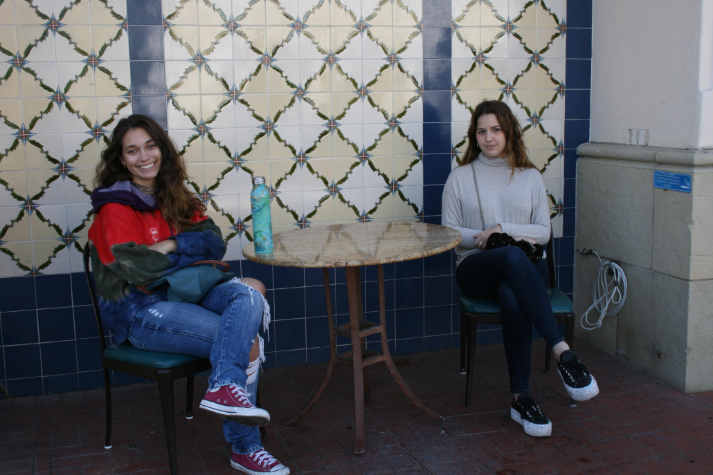 Sandra Maestre and Camila Rojas sit together at a brown round table. 