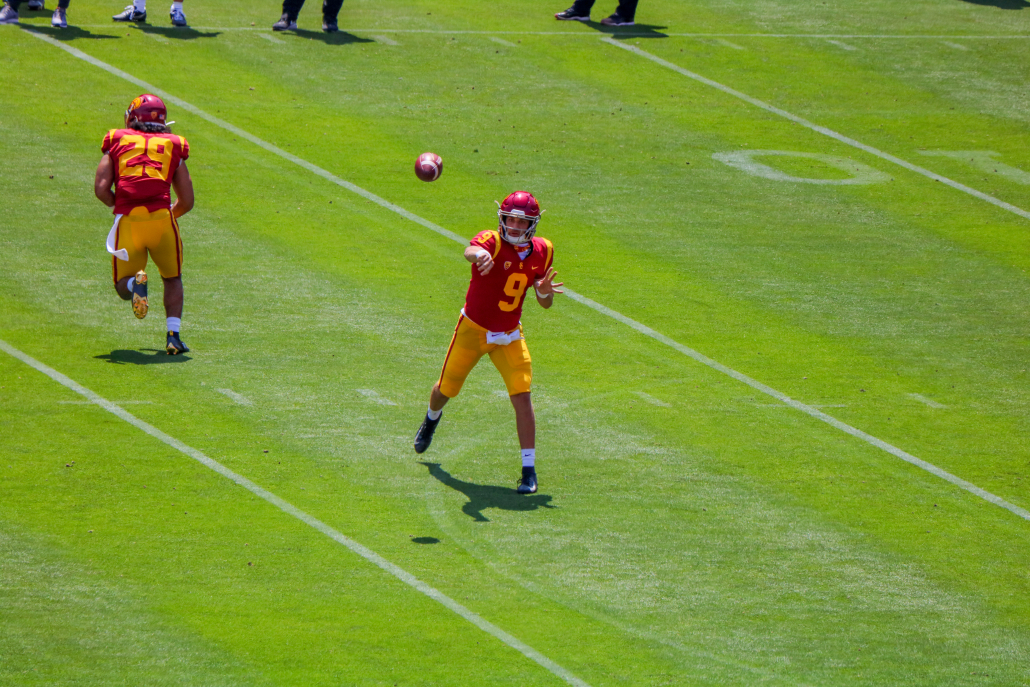 Junior quarterback Kedon Slovis, number 9, follows through after launching a pass during spring football training. Also pictured is redshirt senior running back Vavae Malepeai completing a play-action run fake. 