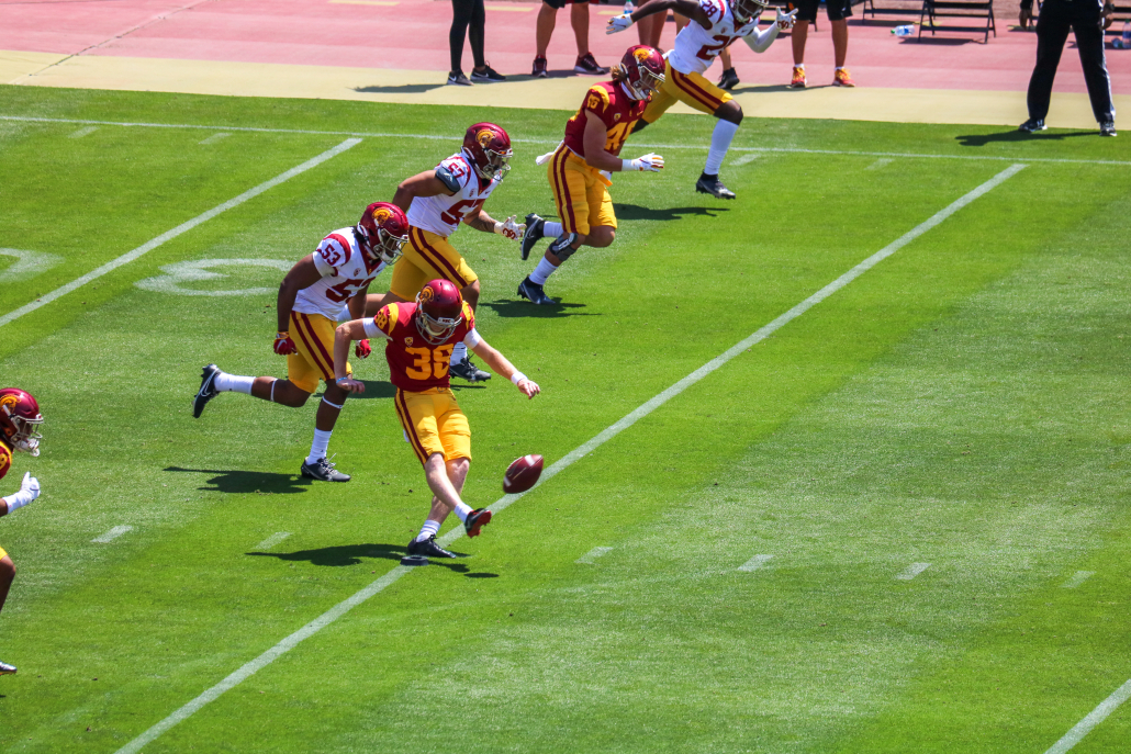 Redshirt junior Alex Stadthaus, number 38, is pictured kicking a ball during USC's spring game. Also pictured are five other USC players running in unison during the kickoff routine.