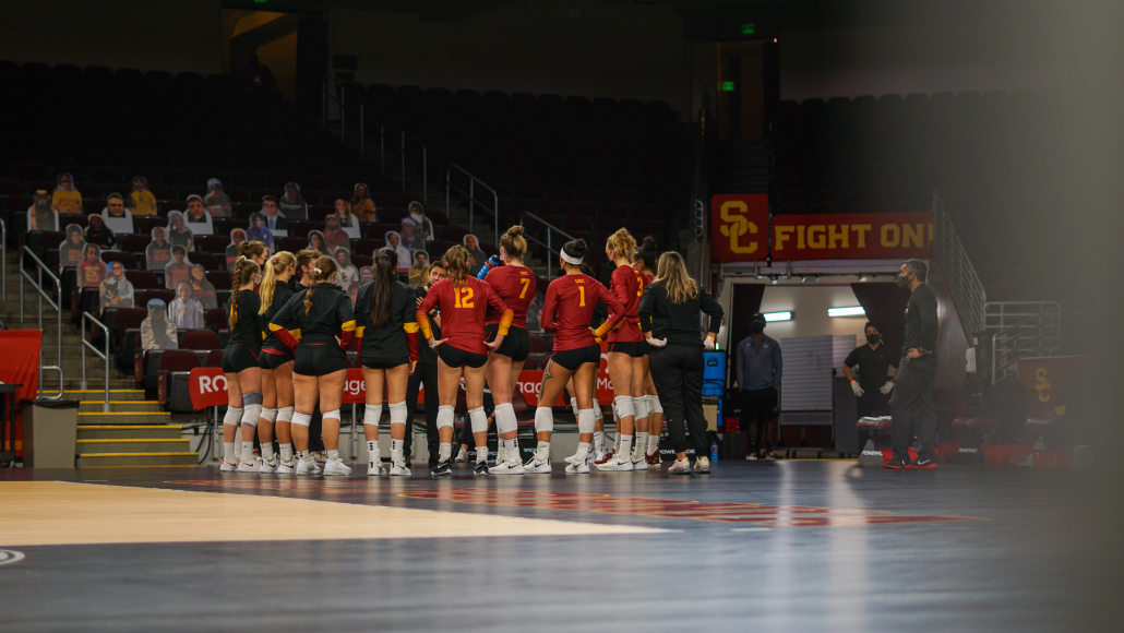 The women's volleyball team is pictured in a huddle as a coach directs them at the Galen Center. 