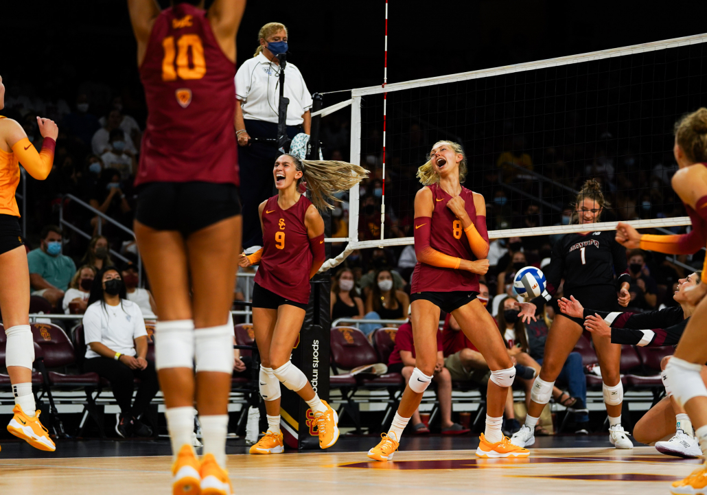 USC women's volleyball players exclaim and celebrate together after winning a point in a match. 