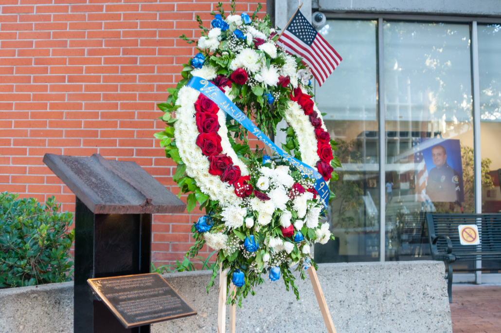Picture of wreath that is green, white and red with an American Flag on it. 