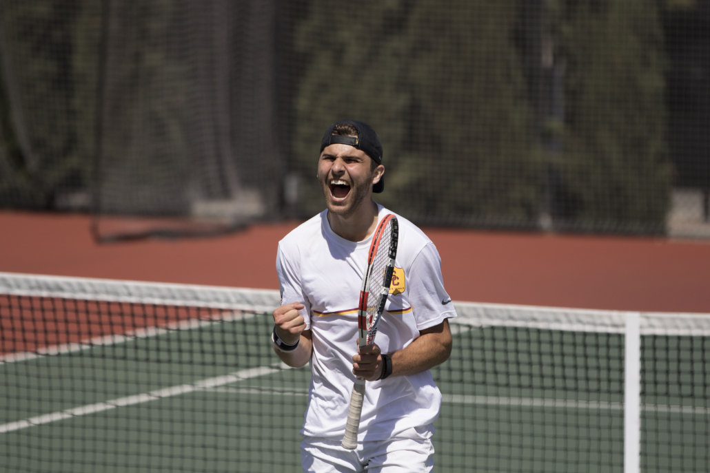 Junior Stefan Dostanic celebrates during a tennis match with his racket in his hand.
