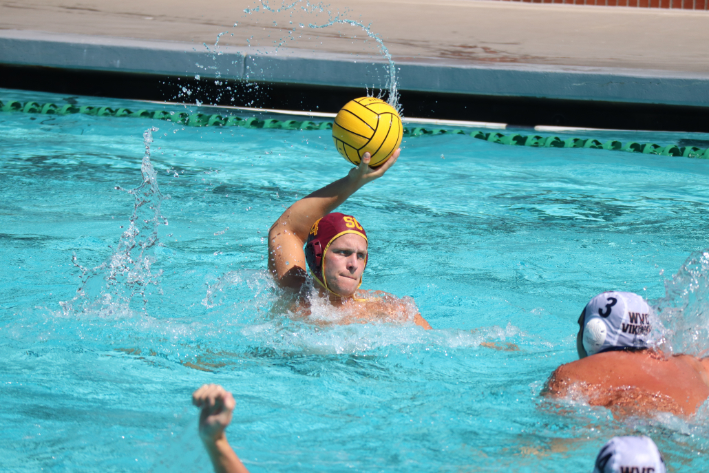 Alexander Lansill, No. 4, is pictured with the ball looking to pass to a teammate. Opposing players defend in front of him. 