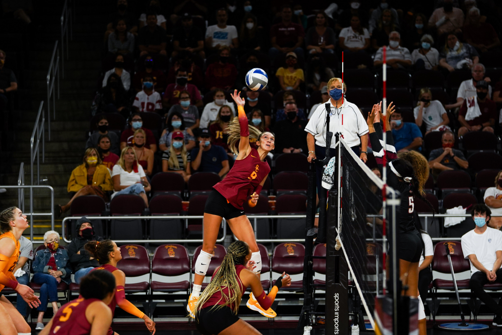 Graduate student Paige Hammons, No. 9, is pictured spiking a ball in the air. Other USC players watch on as opposition defenders try to block the spike.