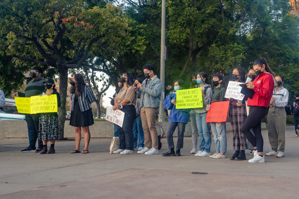 Attendees hold signs that read messages including "Karen Bass, endorse the PHRA - Philippine Human Rights Act!" and "Stop the Killings." 