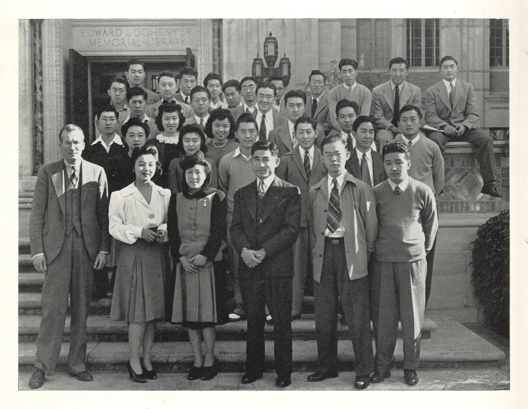 Black-and-white image of a group of Nisei students standing on the steps of Doheny Library.