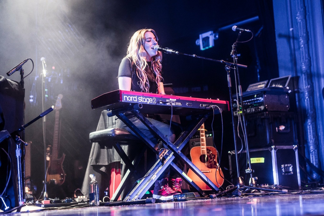 Photo of Sophie Beem on stage. She is singing while playing the keyboard.
