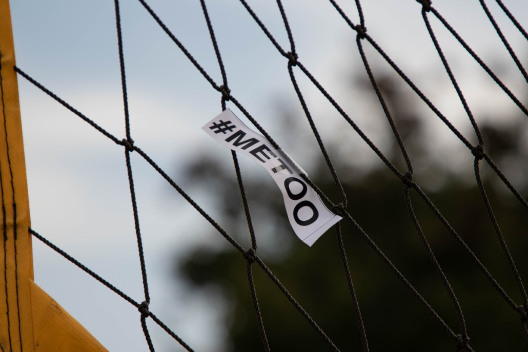Photo of a volleyball net with a paper that says #metoo on it.