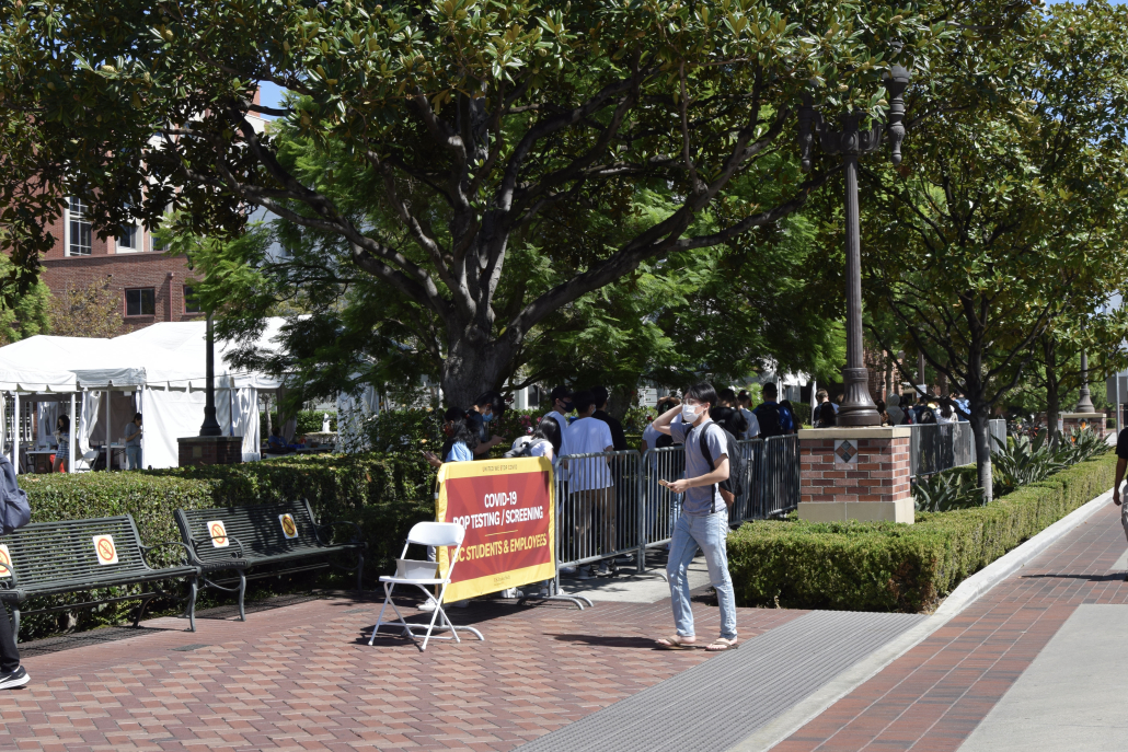 The coronavirus testing line at USC. There are green trees and it's day outside.