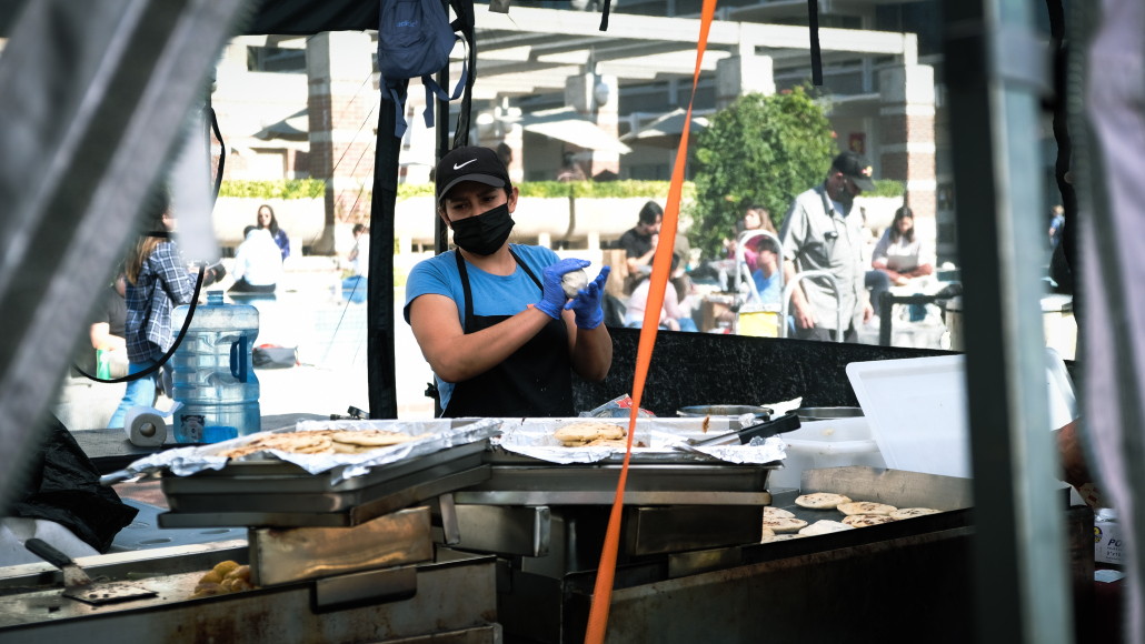 Photo of a woman cooking and rolling dough at the Farmers Market.