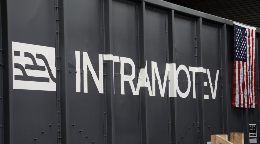 Closeup of railcar with company logo printed on its side, and an American flag hung from top.
