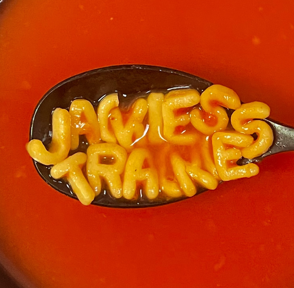 A spoon dipped into a bowl of soup, with the letters noodle (probably spaghetti-o) lined up in the word 