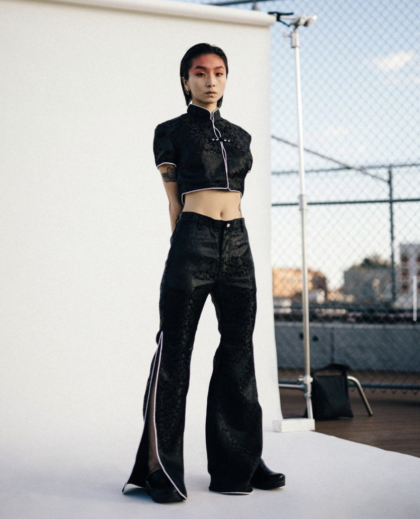 A model in a DAWANG outfit poses against a white backdrop on a city roof.