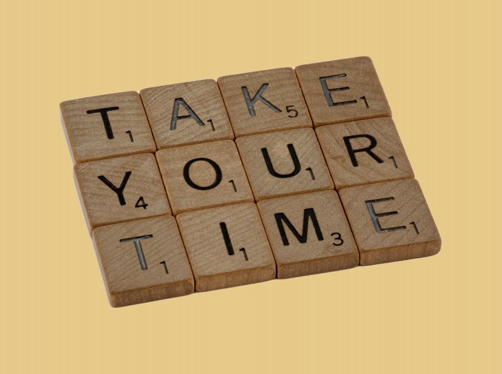 "TAKE YOUR TIME" spelled out with scrabble pieces with a pale yellow background