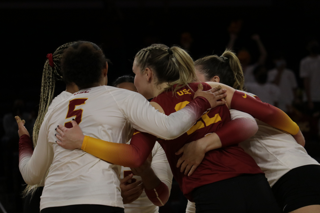 Women's volleyball team join in on a group huddle. 