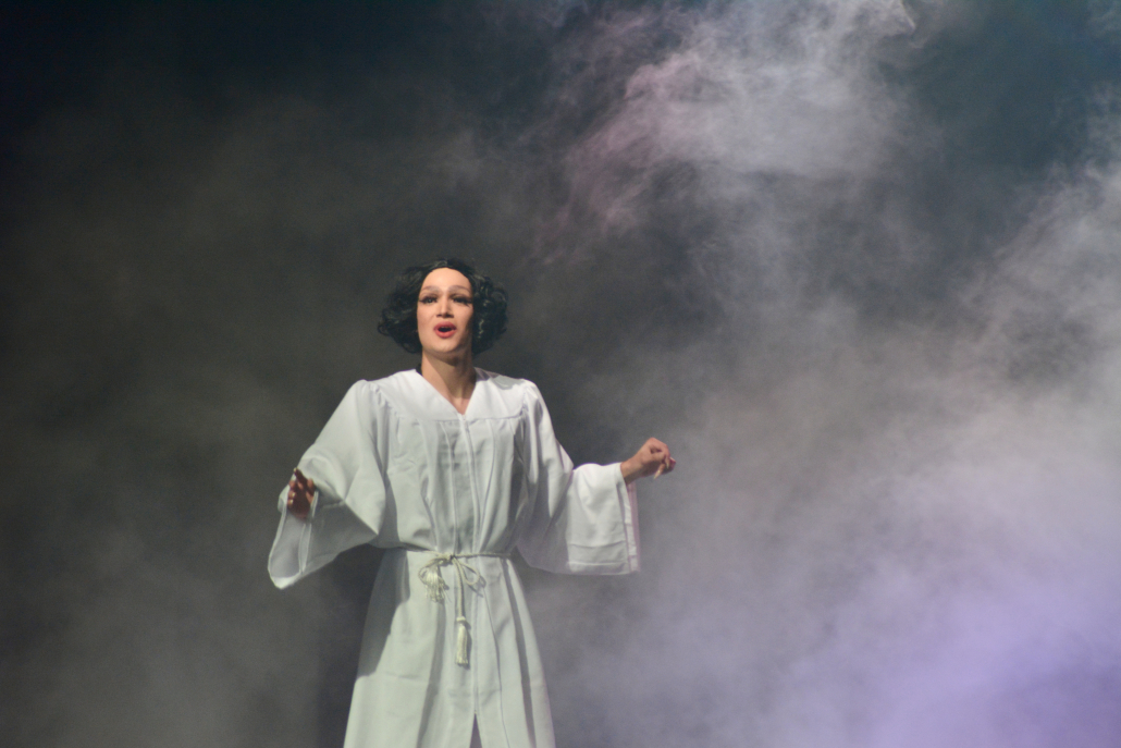 Salma Body stands on stage in a white choir robe.