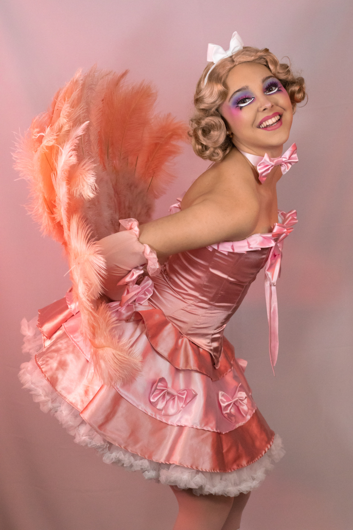 Daisy Darling holds two vintage feather fans behind her to create a peacock-like pose.