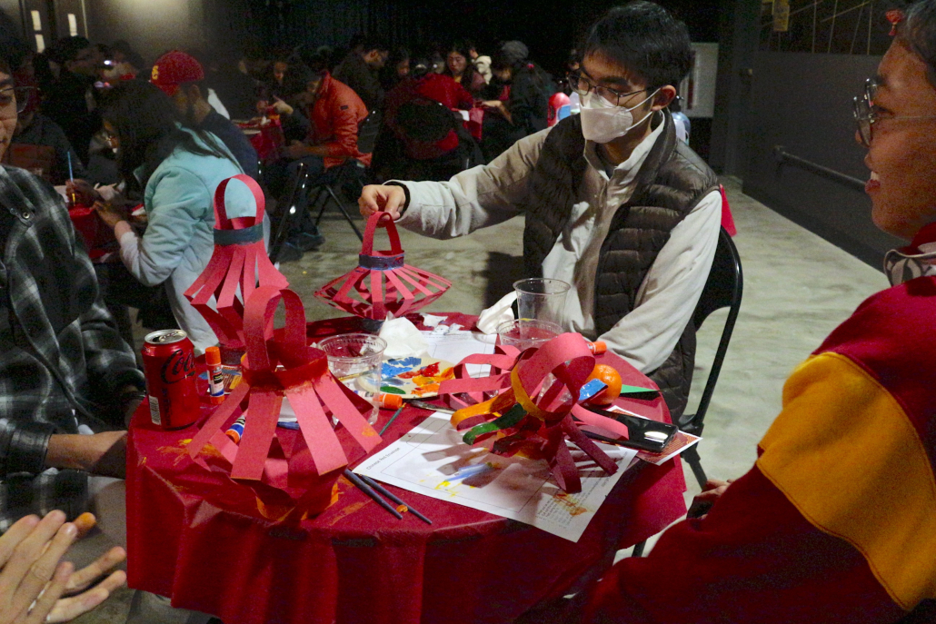 Students making red paper lanterns at a table