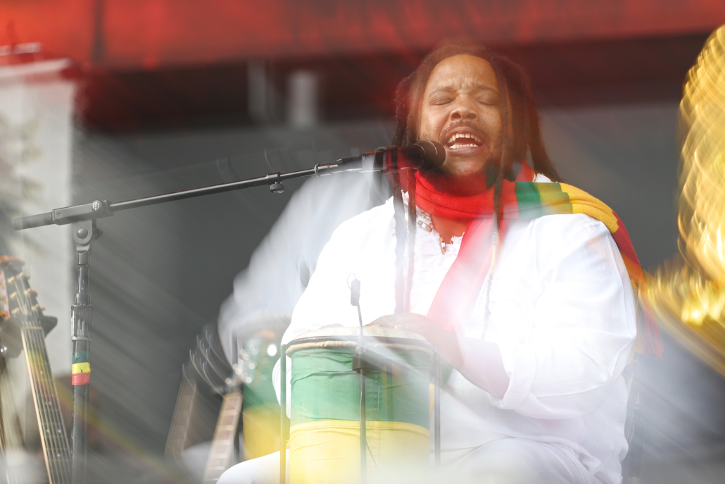 Stephen Marley sings while drumming.