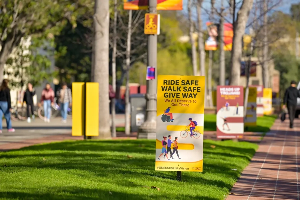 Yellow sign on Trousdale reads, "Ride safe; Walk Safe; Give Way. We all deserve to get there."  