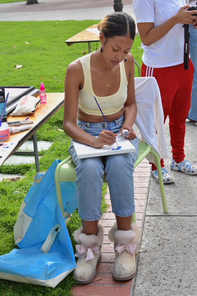 Student paints on canvas while seated.